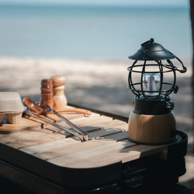 Camping essentials, a vintage kerosene lamp and a modern LED lantern on a wooden table. Enjoy nature